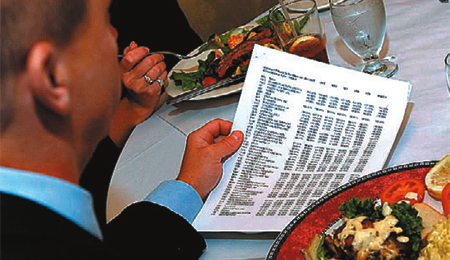 man eating lunch while reading paper